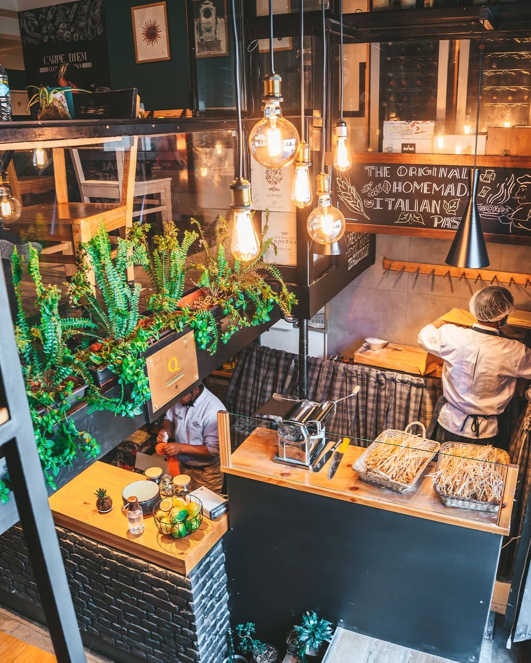 Interior view of Carpe Diem Cucina Italiana in Cusco showcasing the preparation of homemade pasta with ambient lighting and greenery decorations. - The Cusco Guide